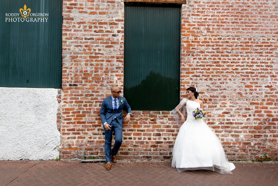 bride and groom posing on a brick wall in the French Quarter New Orleans