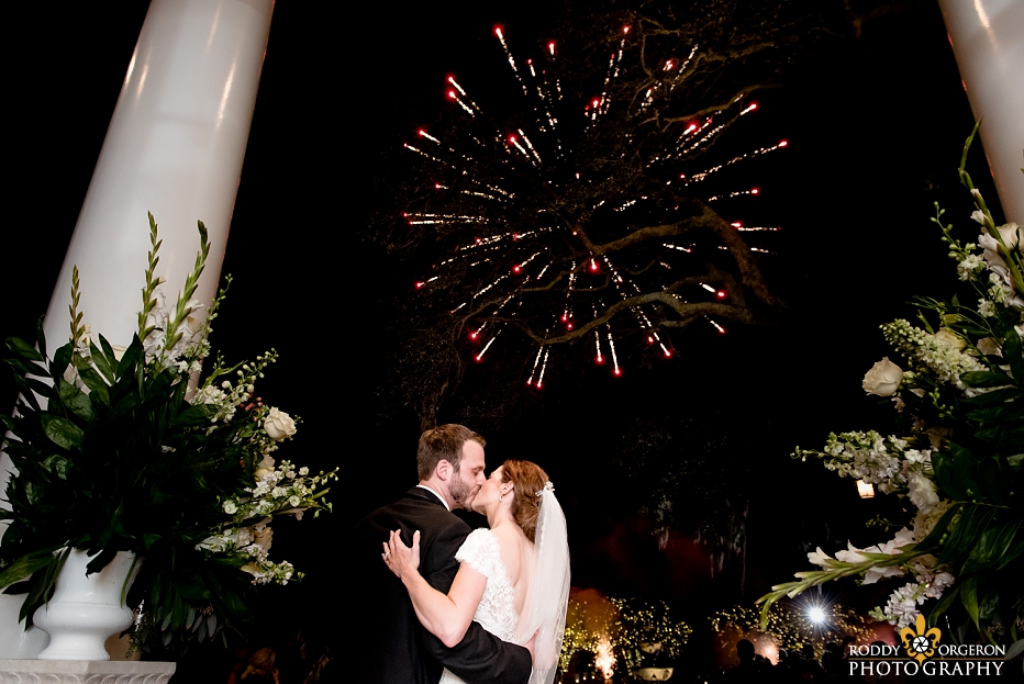 bride and groom kiss at Southern Oaks Plantation with fireworks in the background