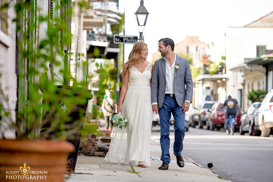 Bride and groom holding hands walking down the street for an engagement session in the French Quarter of New Orleans