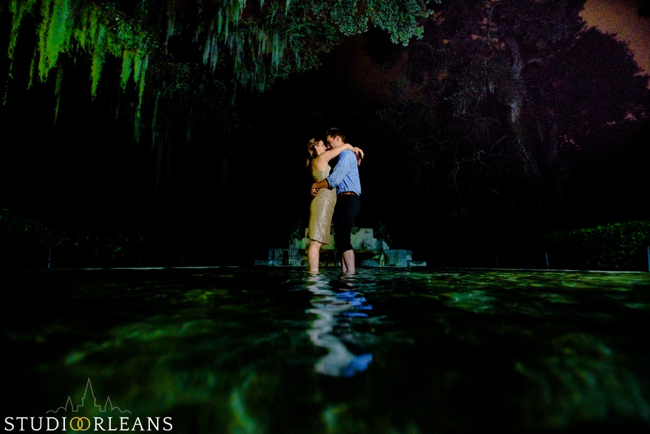 Engaged couple standing under an oak tree in a fountain at Audubon Park in New Orleans