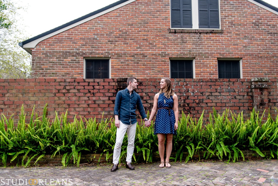 A couple standing in front of a cool brick wall with ferns in New Orleans