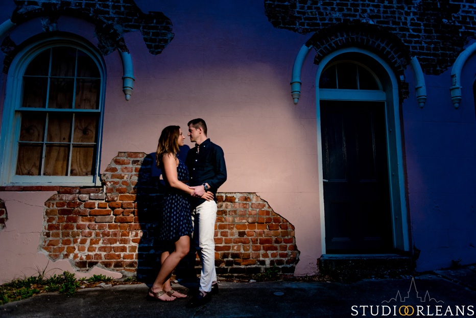 A couple standing on a sidewalk in New Orleans for an engagement session in front of a cool building