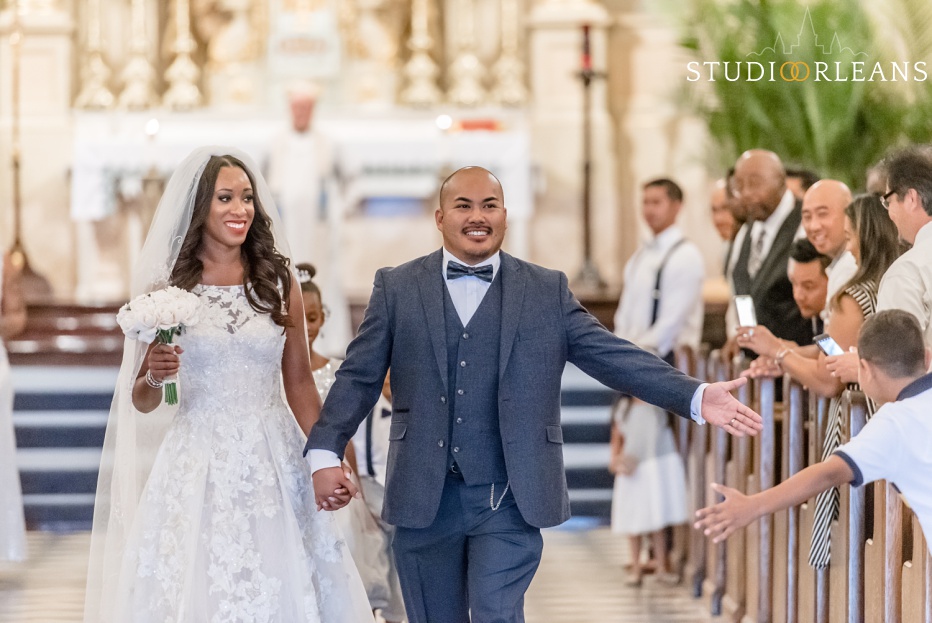 A bride and groom walk out of the Saint Louis Cathedral after they say "I Do"