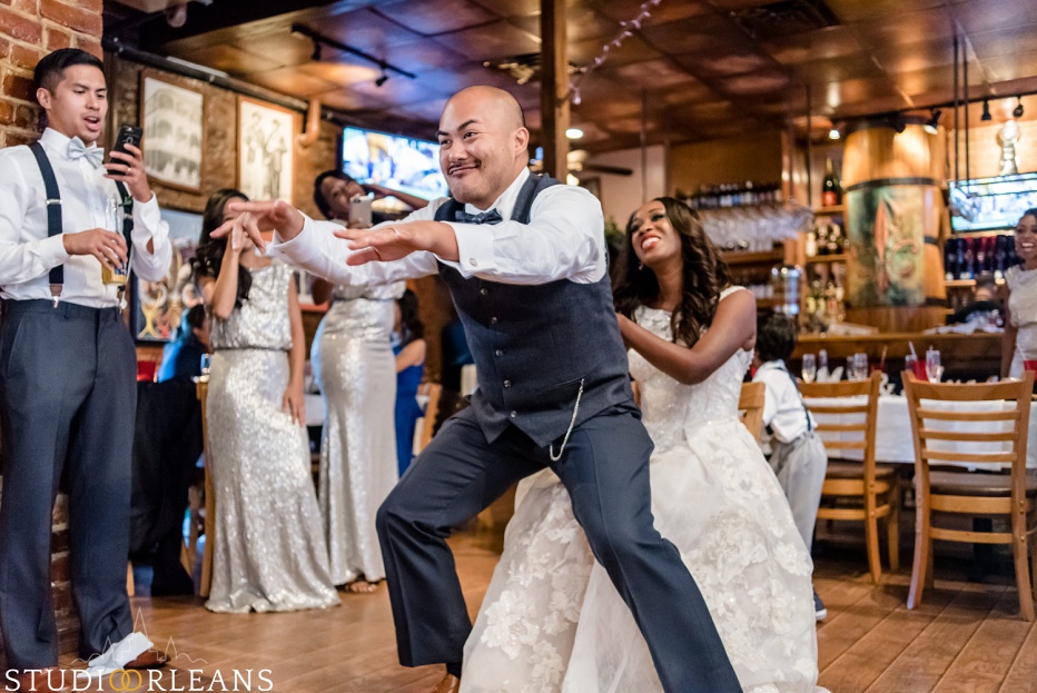 The groom dances on his bride acting silly at Oceana Grill in the French Quarter of New Orleans