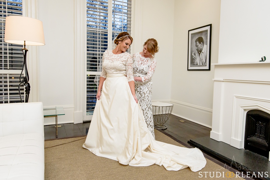 A mother helps her daughter get her wedding dress on before her wedding