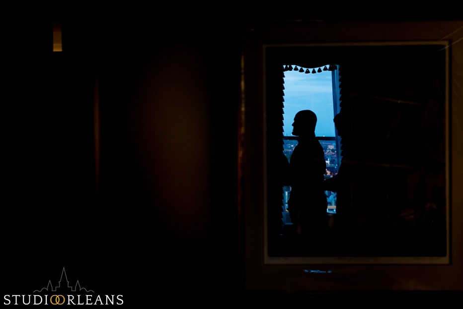 A silhouette of a groom getting ready by a window