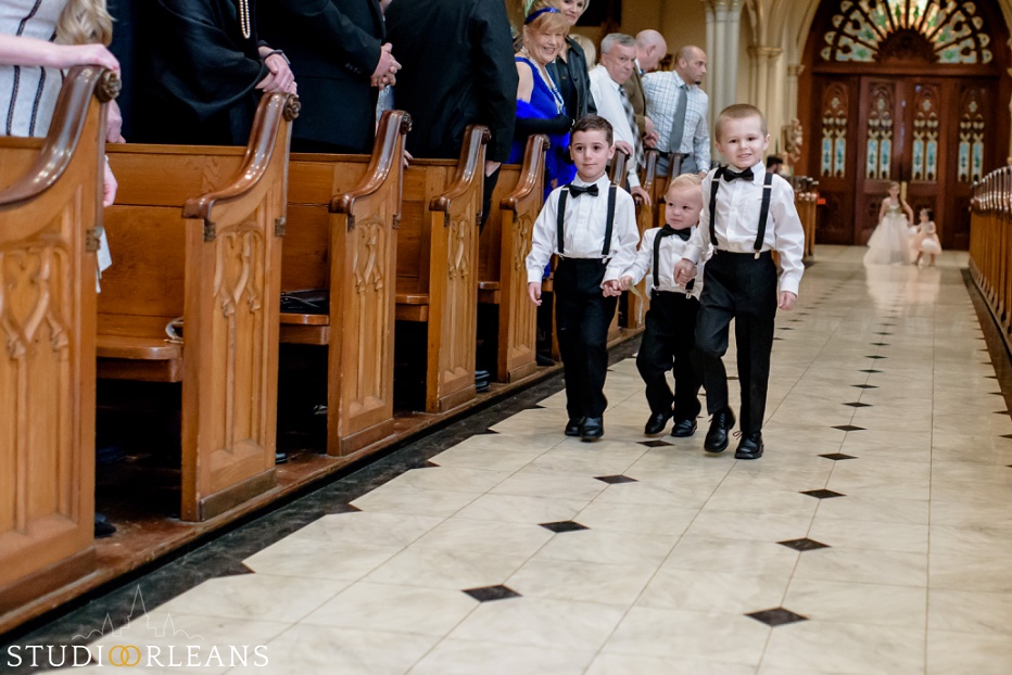 Junior groomsmen and junior bridesmaids walk down the aisle in church for the wedding ceremony