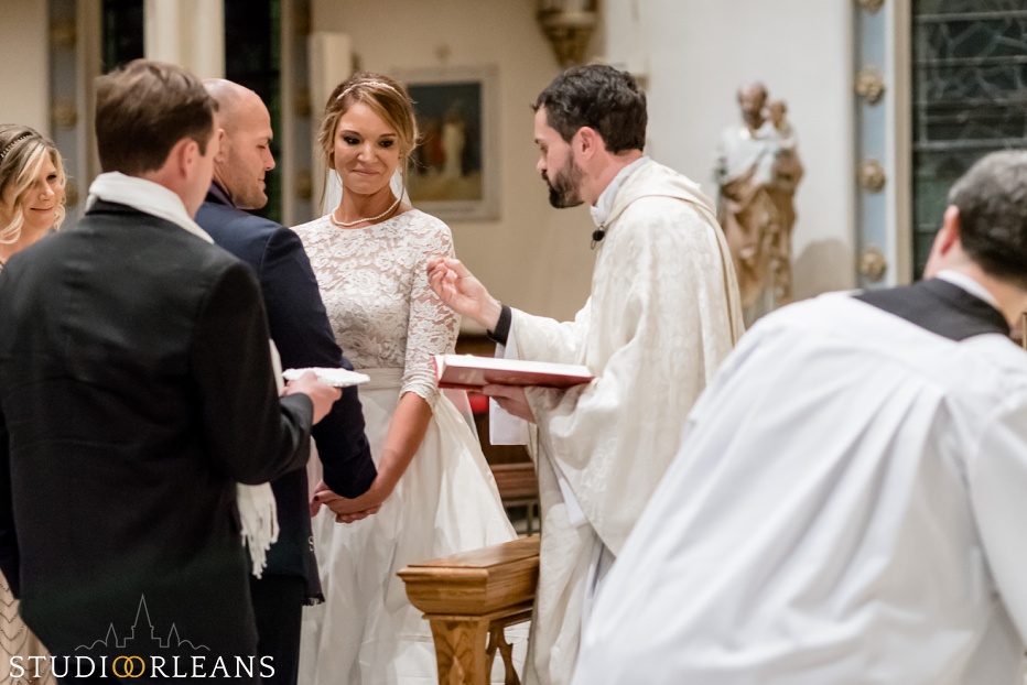 The priest shows something to the bride and groom
