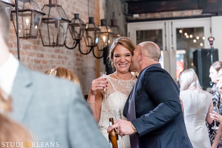 The groom reaches over and gives his bride a kiss at Belovo lights in New Orleans