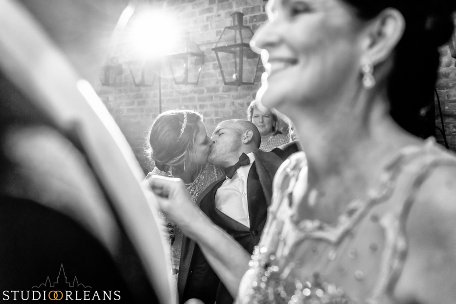 The groom reaches over and gives his bride a kiss at Belovo lights in New Orleans