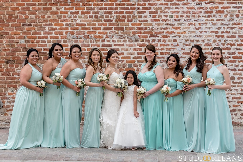 The bride and bridesmaids pose for a picture against this beautiful brick wall in New Orleans