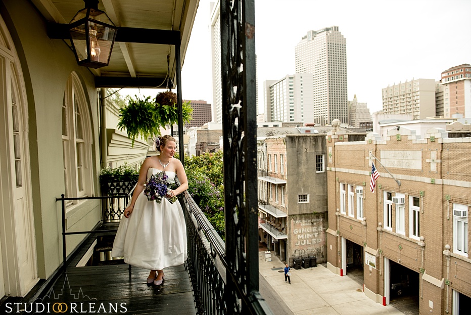 The bride over looks the balcony in the French Quarter of New Orleans before her ceremony