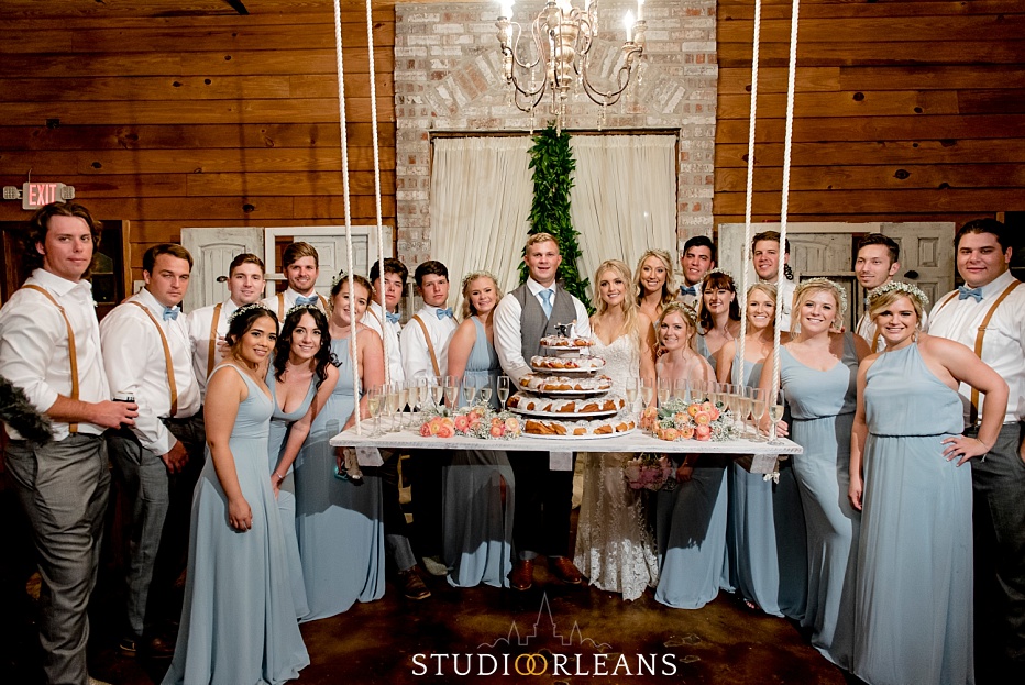 The bridal party poses for a picture in front of the wedding cake