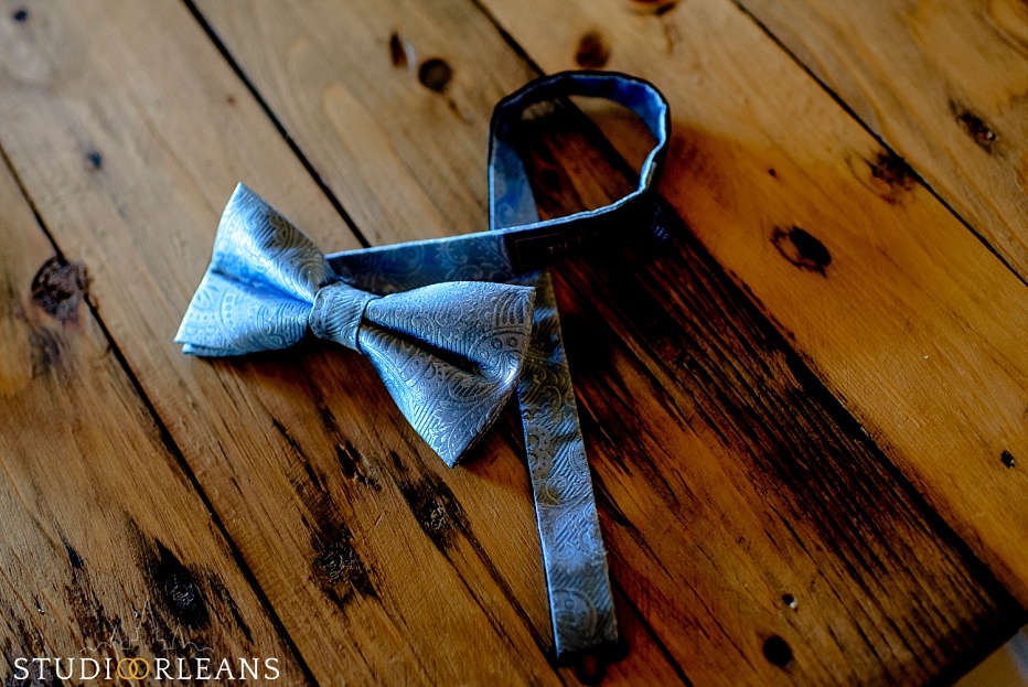 The grooms bow tie lays on the beautiful wood floor at the Berry Barn
